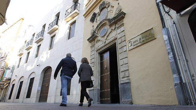 Dos personas pasan por delante de la sede de la Junta