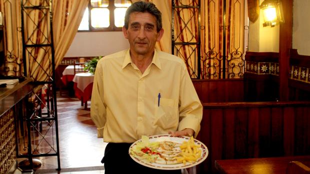 Un camarero del Timón de Cabra enseña su plato estrella: el calamar a la plancha relleno de bacón
