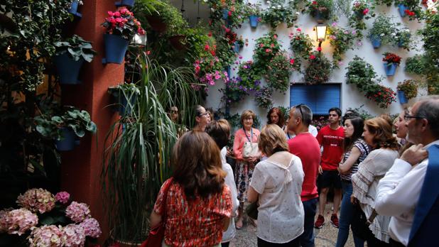 Visitantes de una ruta en el patio de la calle Martín de Roa, 2 oyen atentamente a su guía