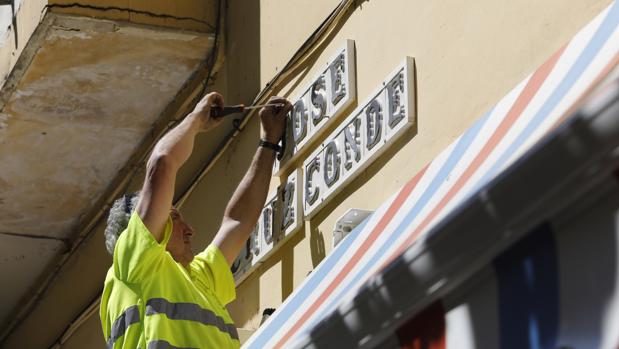 Un operario de Movilidad retira el rótulo de la calle Cruz Conde
