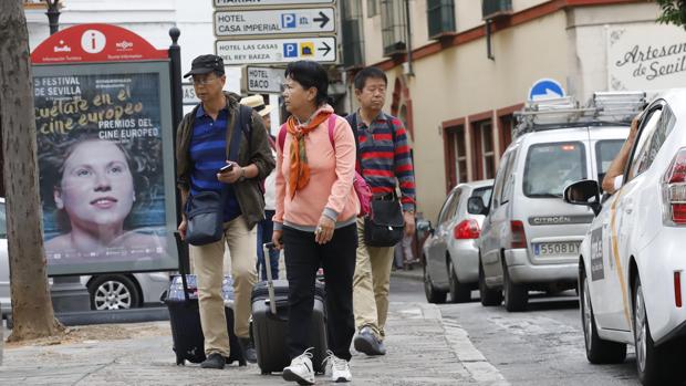 Varios turistas tiran de sus maletas por una de las calles de Sevilla