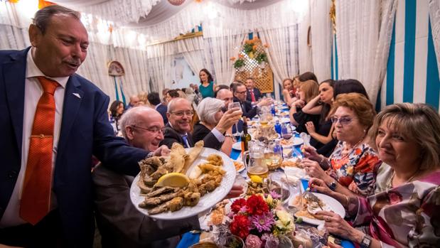 Socios de una caseta de la Feria de Abril disfrutando de la noche del «pescaíto»